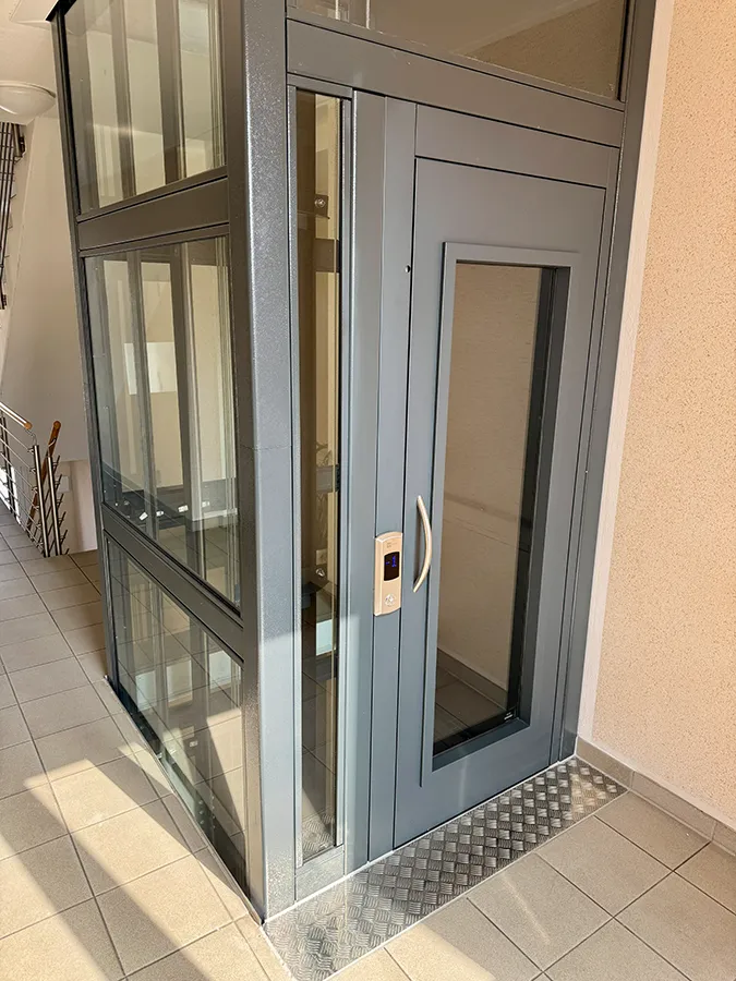 Moderner Homelift Aufzug in einem Wohngebäude, graues Design mit Glastüren