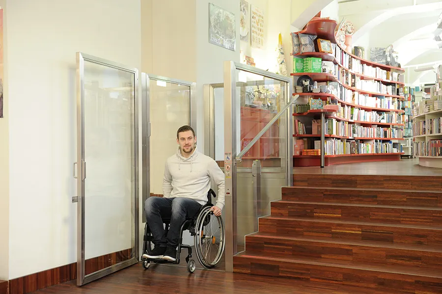 Rollstuhl-Hebebühne in einem öffentlichen Gebäude neben einer Treppe